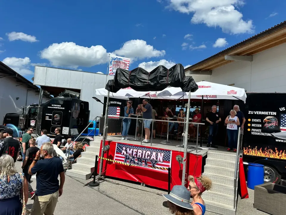 Besucherinnen und Besucher an der roten Theke der US Truck-Bar