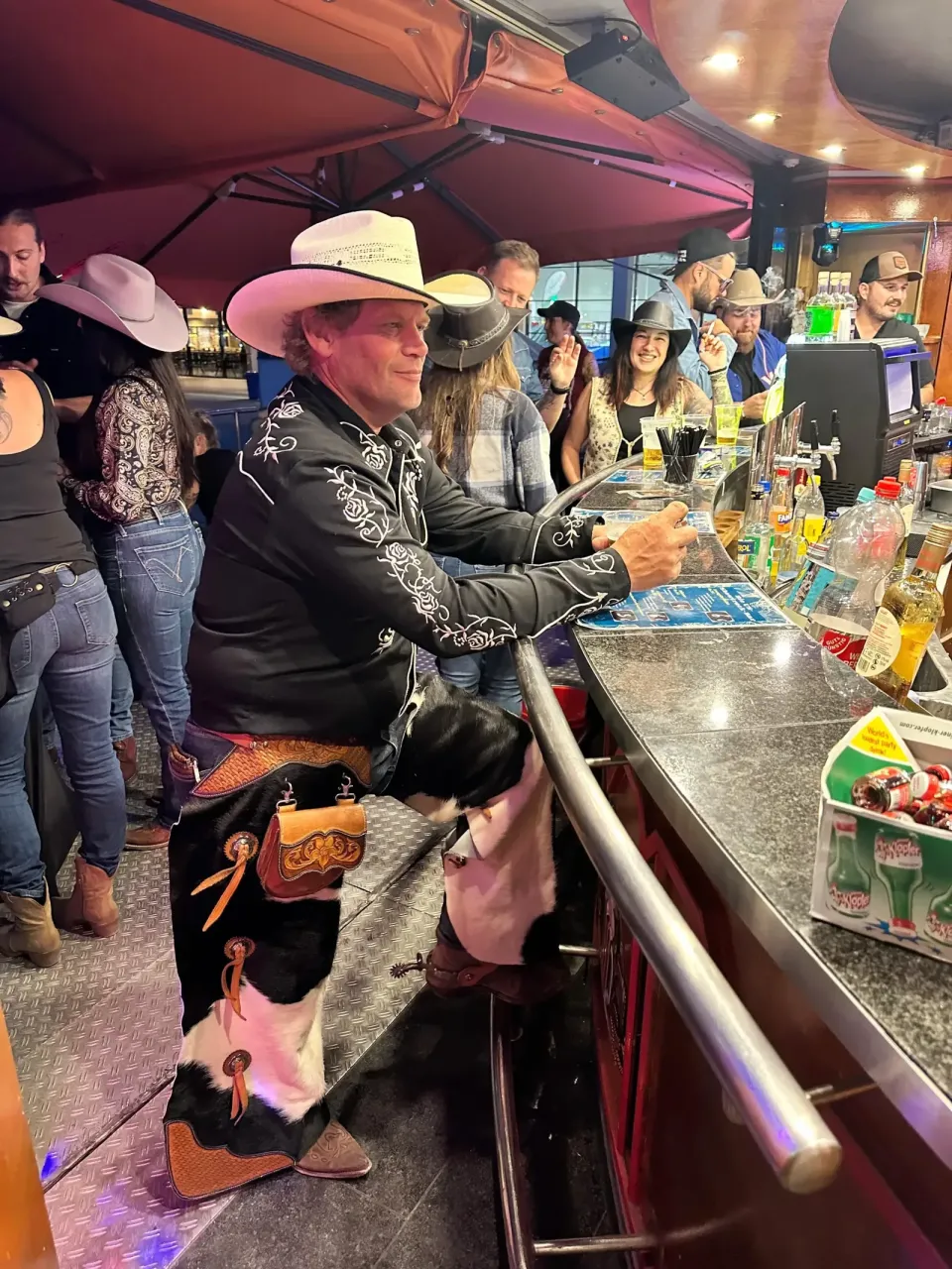 Gast mit Cowboyhut am mechanischen Bullen neben der Bar