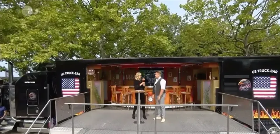 Die Truck-Bar mit US-Flagge und Barhockern im Grünen
